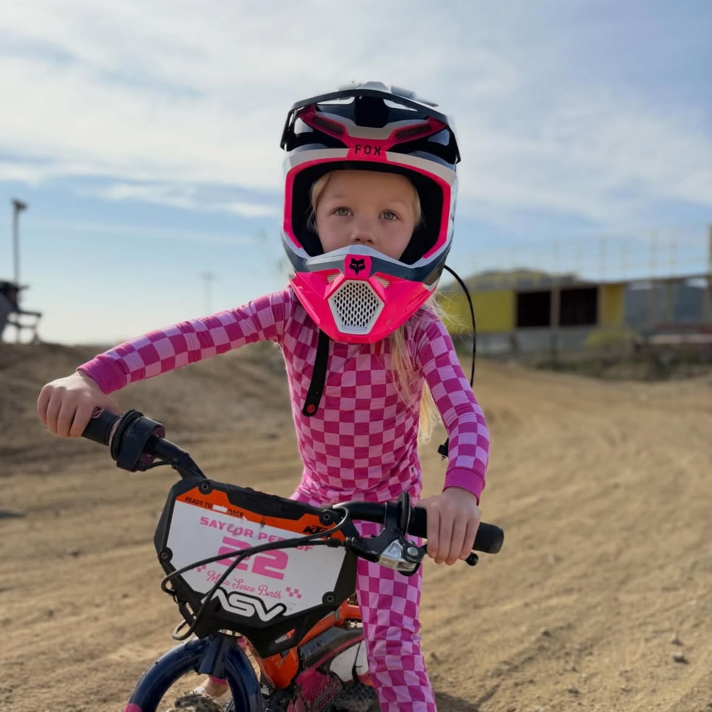 Girl in pink checkered gear on her dirt bike at the track, Moto Since Birth number plate